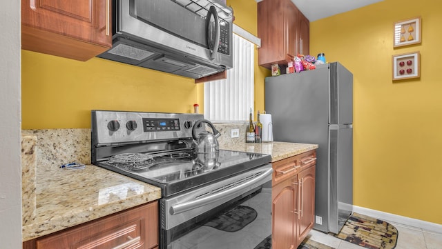 kitchen with light stone countertops, appliances with stainless steel finishes, and light tile patterned floors