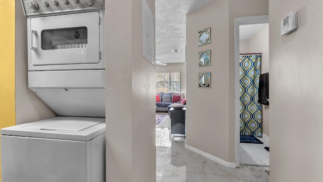 laundry room featuring stacked washer / dryer and a textured ceiling