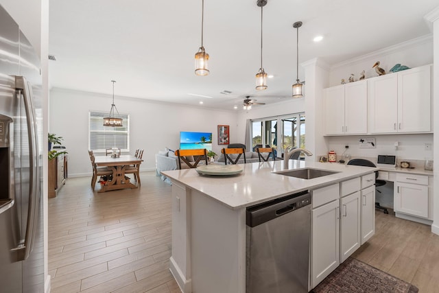 kitchen with sink, appliances with stainless steel finishes, hanging light fixtures, an island with sink, and white cabinets