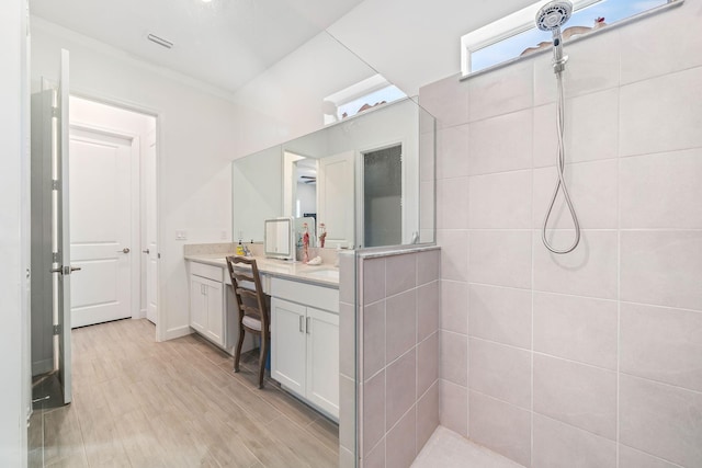 bathroom with vanity, wood-type flooring, and tiled shower