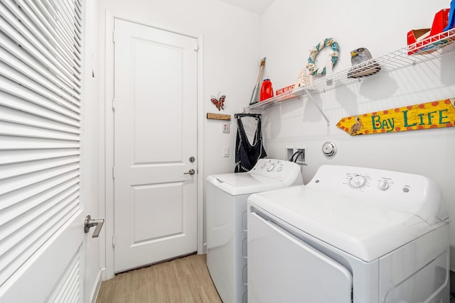 laundry room with separate washer and dryer and light hardwood / wood-style floors