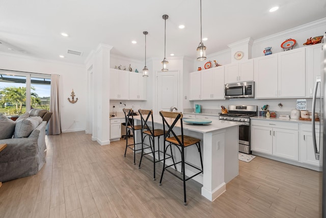 kitchen with a kitchen bar, a kitchen island, pendant lighting, stainless steel appliances, and white cabinets