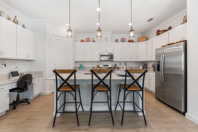 kitchen with hanging light fixtures, white cabinets, and appliances with stainless steel finishes