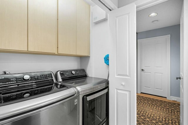 clothes washing area featuring cabinets and washer and clothes dryer