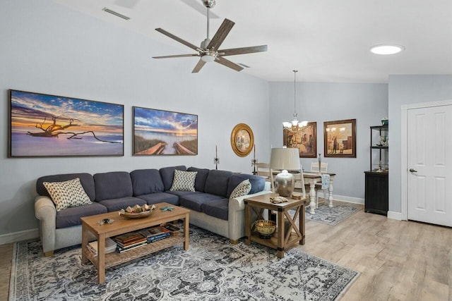 living room with lofted ceiling, hardwood / wood-style floors, and ceiling fan with notable chandelier