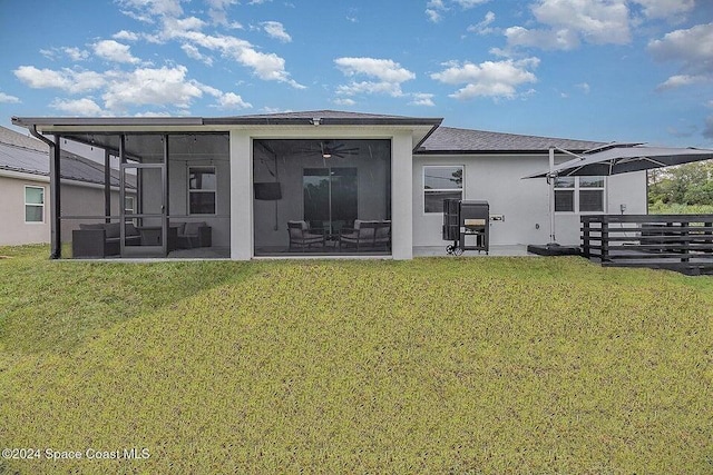 back of house featuring ceiling fan, a sunroom, and a lawn