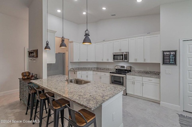 kitchen with stainless steel appliances, sink, a breakfast bar area, and white cabinets