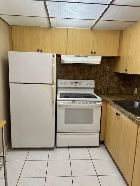 kitchen featuring backsplash, white appliances, sink, and light tile patterned floors