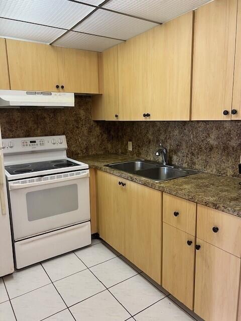 kitchen featuring tasteful backsplash, sink, light tile patterned floors, and white range with electric stovetop