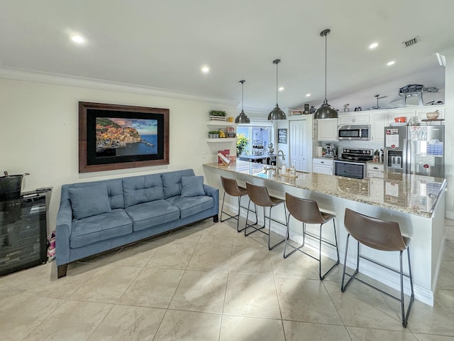 kitchen featuring pendant lighting, crown molding, white cabinetry, stainless steel appliances, and a kitchen breakfast bar