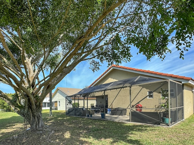 rear view of property featuring a yard, a lanai, and a patio