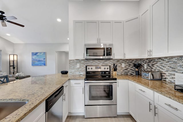 kitchen with stainless steel appliances, white cabinetry, tasteful backsplash, and light stone counters