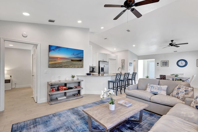 living room with vaulted ceiling, ceiling fan, and light hardwood / wood-style floors