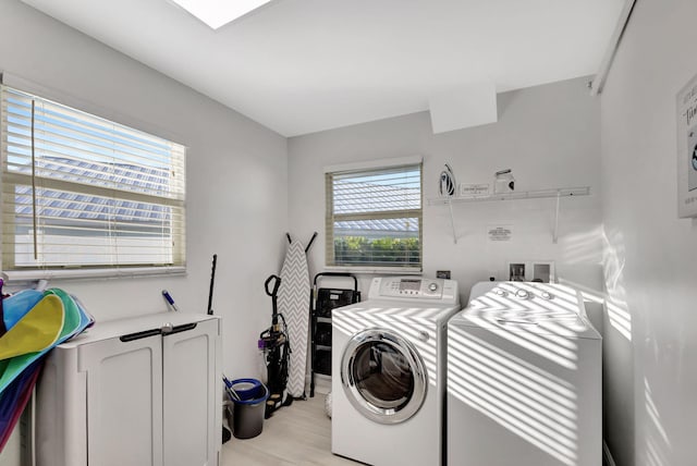 clothes washing area with independent washer and dryer and light wood-type flooring