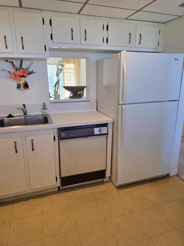 kitchen with sink, white appliances, light tile patterned floors, and white cabinets