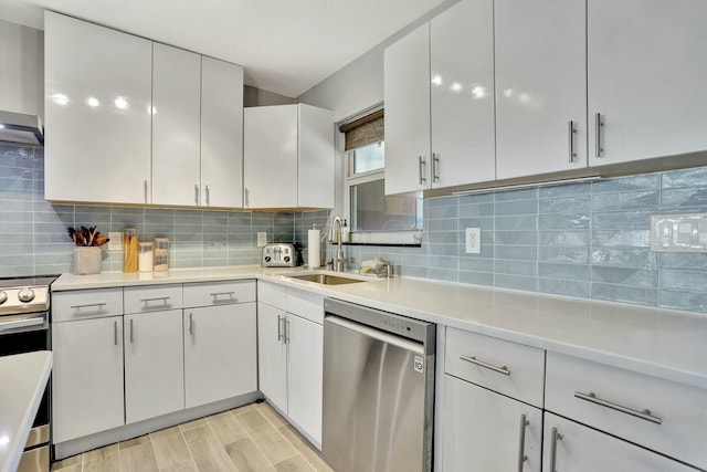 kitchen featuring sink, white cabinetry, stainless steel appliances, decorative backsplash, and wall chimney exhaust hood