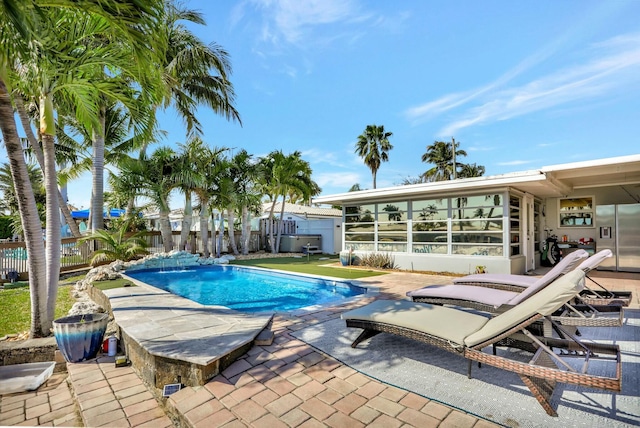 view of swimming pool with pool water feature, a sunroom, and a patio area