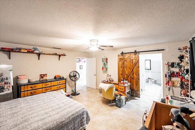 bedroom with a barn door, connected bathroom, a textured ceiling, and ceiling fan