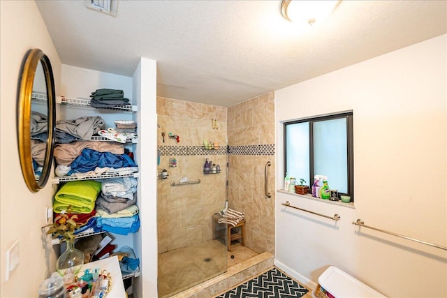 bathroom with tiled shower and a textured ceiling