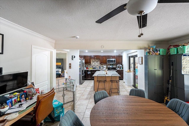 dining space featuring crown molding, light tile patterned floors, a textured ceiling, and ceiling fan