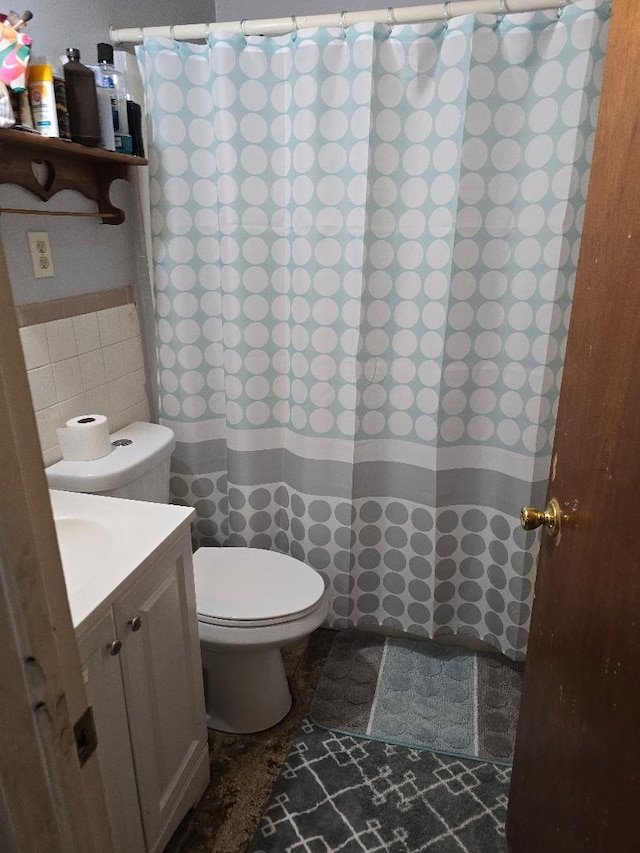 bathroom featuring vanity, toilet, and tile walls