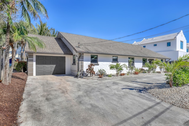 ranch-style house with a garage, concrete driveway, a shingled roof, and stucco siding