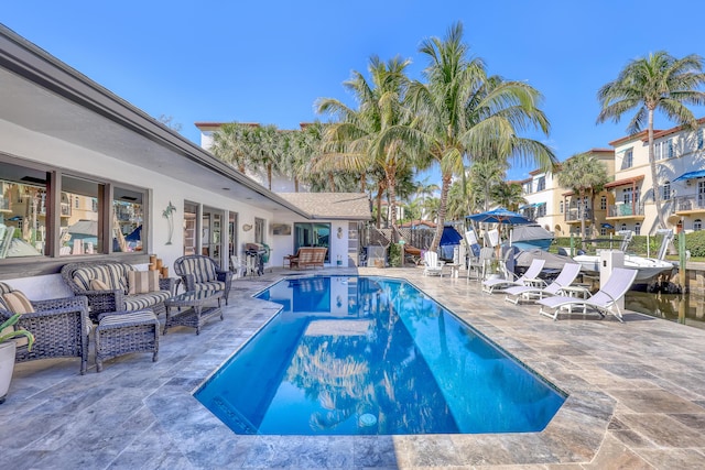 pool with a patio area, grilling area, fence, and an outdoor living space