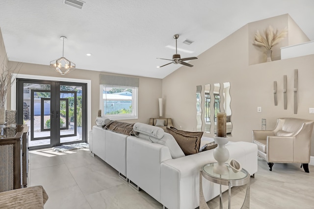 living area featuring ceiling fan with notable chandelier, visible vents, vaulted ceiling, and french doors