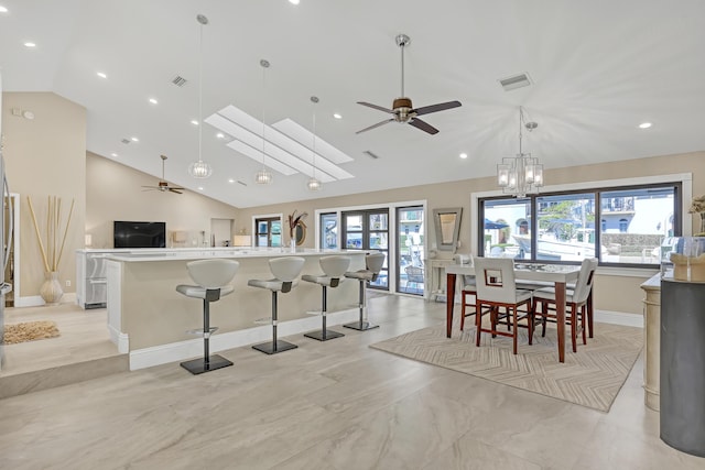 dining area with ceiling fan with notable chandelier, high vaulted ceiling, and visible vents