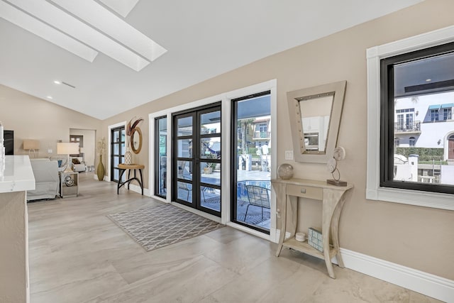 entryway featuring french doors, lofted ceiling with skylight, and baseboards