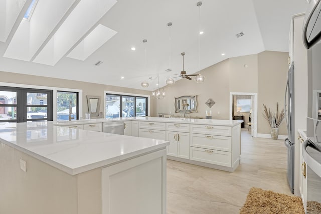 kitchen with light stone counters, a skylight, white cabinets, dishwasher, and decorative light fixtures