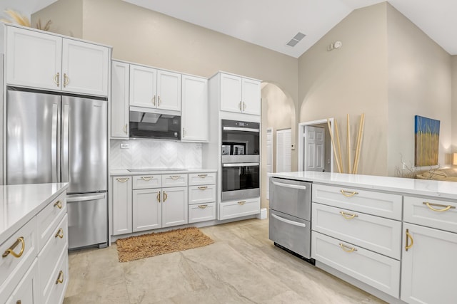 kitchen with appliances with stainless steel finishes, white cabinets, light countertops, and vaulted ceiling