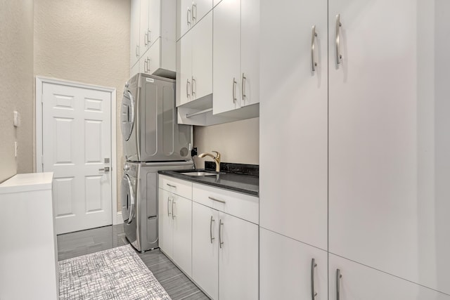 interior space with dark countertops, white cabinets, a sink, and stacked washer / drying machine