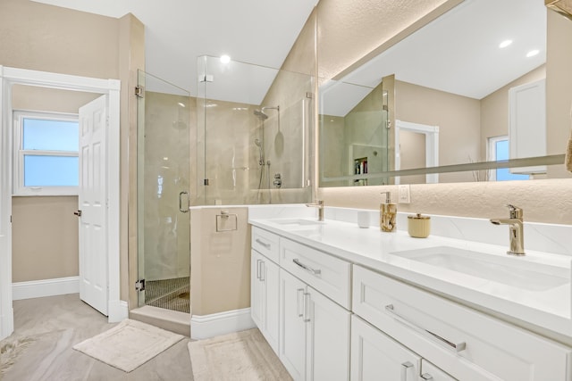 full bathroom with double vanity, a stall shower, a sink, and lofted ceiling