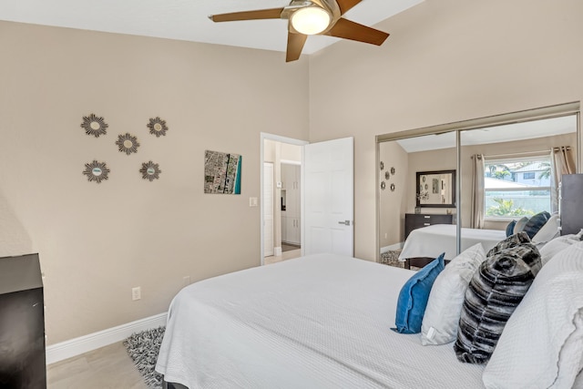 bedroom featuring high vaulted ceiling, a ceiling fan, baseboards, and a closet