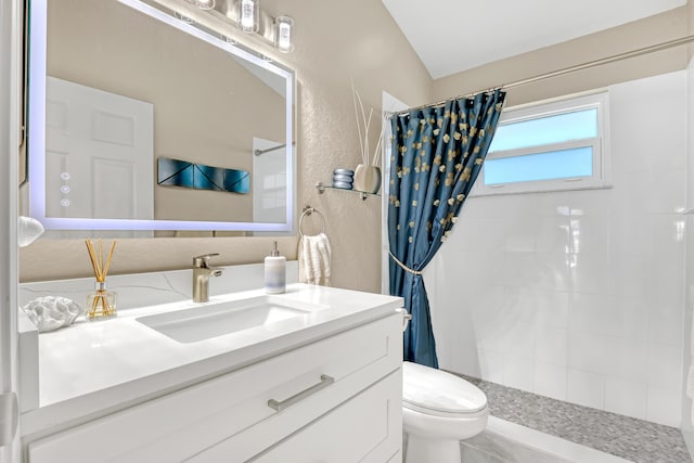 bathroom featuring tiled shower, a textured wall, vanity, and toilet