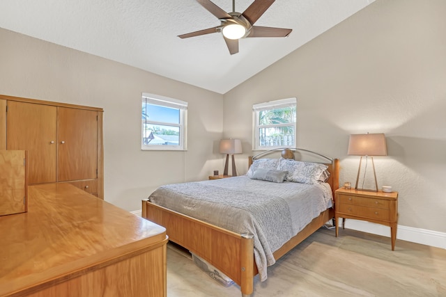 bedroom featuring lofted ceiling, multiple windows, ceiling fan, and baseboards