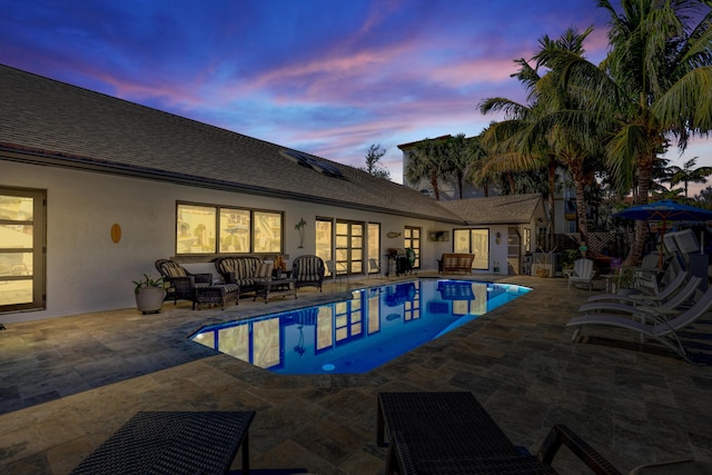 pool at dusk with an outdoor pool, outdoor lounge area, and a patio