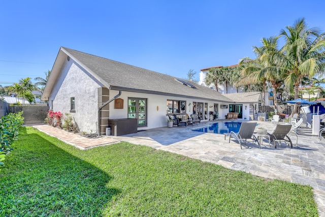 rear view of property featuring stucco siding, an outdoor pool, a lawn, and fence