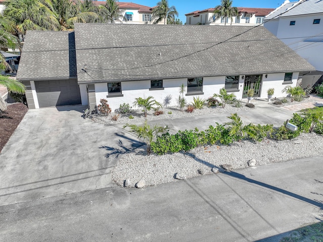 view of front of property with an attached garage, stucco siding, concrete driveway, and roof with shingles