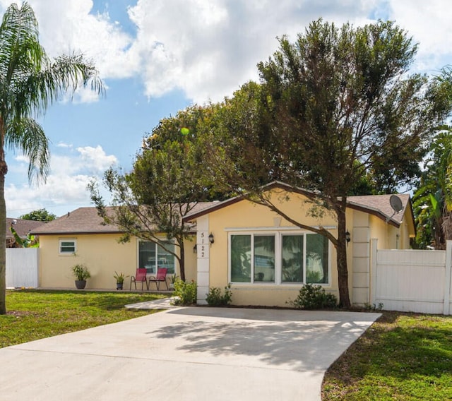 single story home featuring fence, a front lawn, and stucco siding