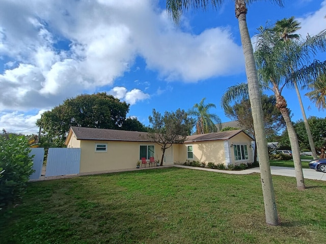 ranch-style house featuring a front yard, fence, and stucco siding