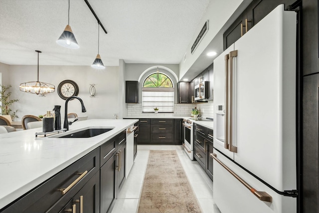 kitchen featuring decorative light fixtures, sink, backsplash, high end appliances, and light stone counters