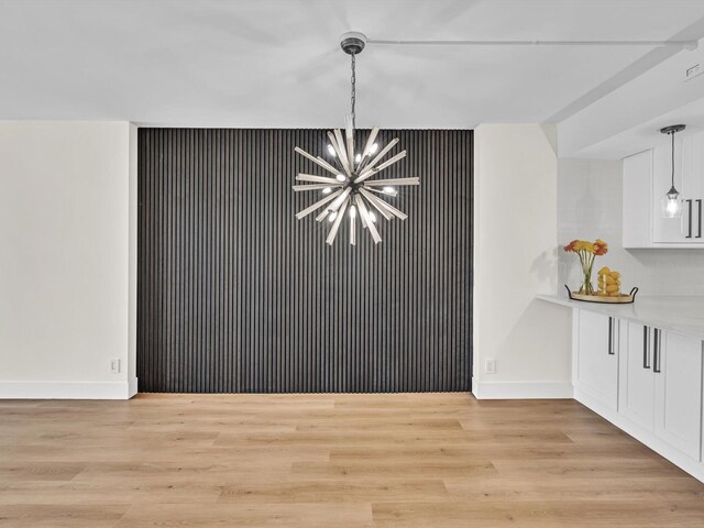 unfurnished living room featuring light wood-type flooring, baseboards, visible vents, and a notable chandelier