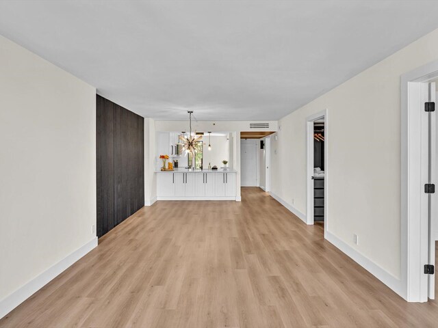 kitchen with white cabinetry, a chandelier, light hardwood / wood-style flooring, kitchen peninsula, and pendant lighting