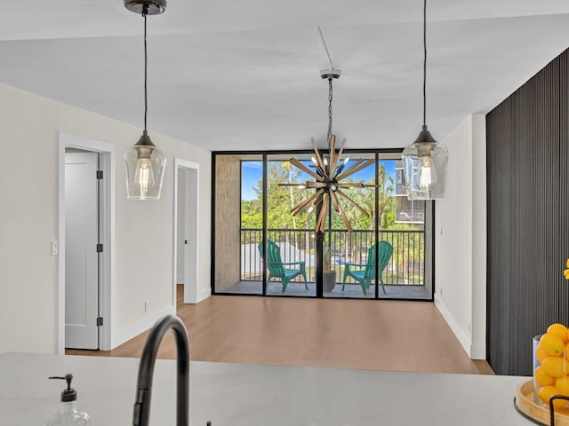 kitchen with pendant lighting, a wall of windows, wood finished floors, and baseboards