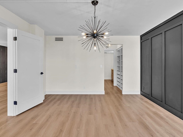 interior space featuring a chandelier, built in shelves, visible vents, baseboards, and light wood-style floors