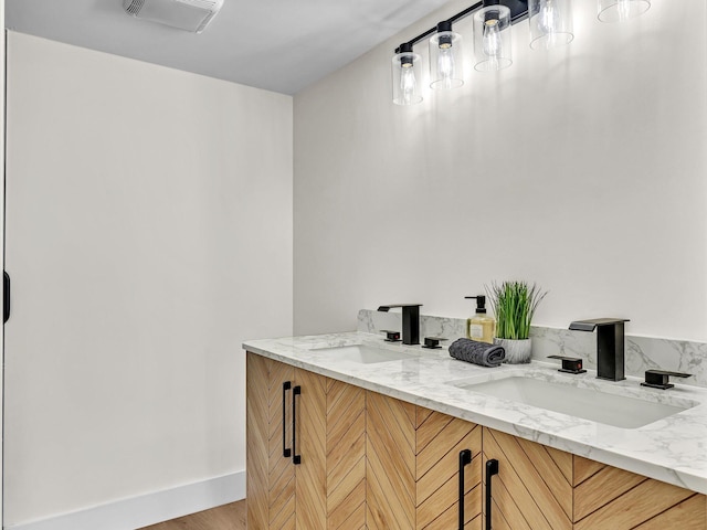 bathroom with double vanity, a sink, visible vents, and baseboards