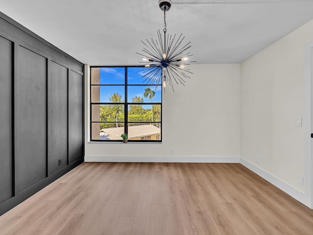 unfurnished bedroom with a chandelier and light hardwood / wood-style floors