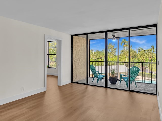 unfurnished room featuring floor to ceiling windows, baseboards, and wood finished floors